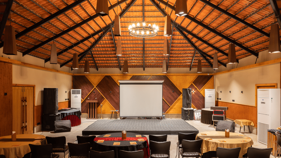 Wide-angle shot of a conference room with a stage, projection screen, and seating arranged in a semi-circle at Hotel Sonar Bangla, Sundarban.