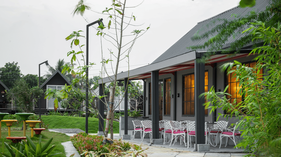 Exterior view of a Hotel Sonar Bangla, Taki with a sloping roof, featuring an outdoor seating patio.