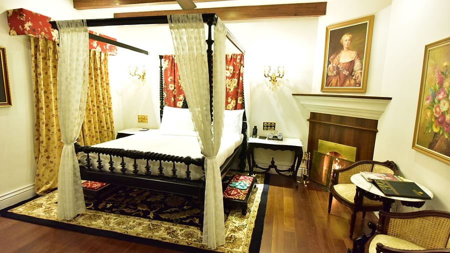 a king size bed with the fireplace on its right side and a wall painting hanging above the fireplace - Mayfair Himalayan Spa Resort Kalimpong 1