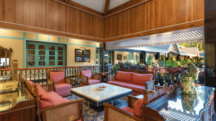 Warm timber-panelled lounge with plush pink and red seating at Mayfair Manor, Jungpana.