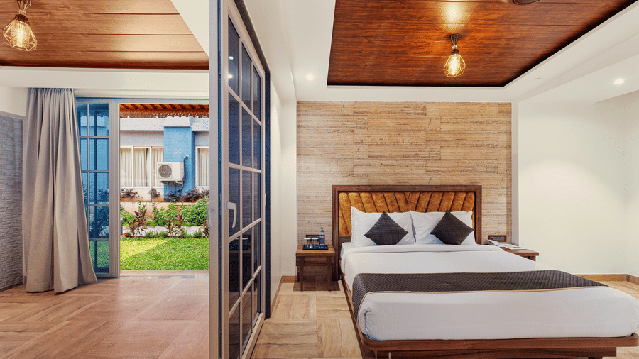Bright bedroom at Mayur Retreat and Spa with a large bed, wooden flooring, and glass doors that open to a private patio.