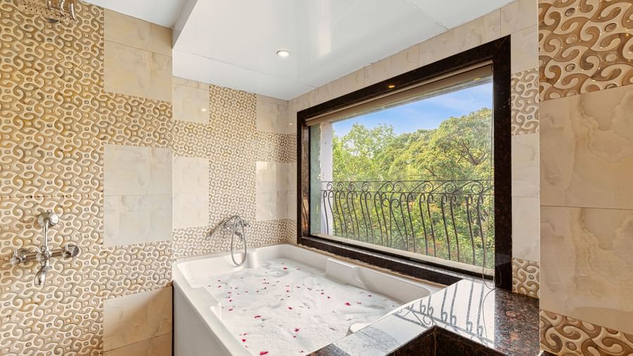 Luxurious bathroom featuring a large bathtub by a window with scenic outdoor views at Mayur Retreat.
