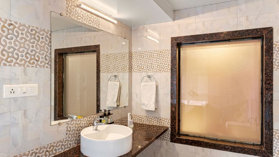 Modern bathroom at Mayur Retreat featuring a vessel sink, patterned tiles, and a large framed mirror.