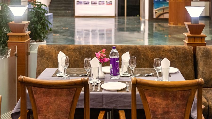 Cosy restaurant seating with elegantly set tables, and a warm ambience at Mayur Retreat.