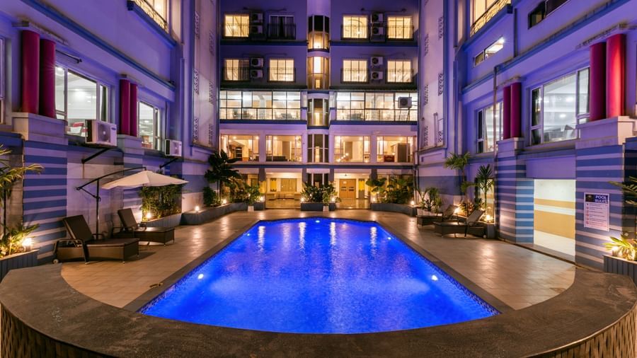 Long view of a swimming pool at Mayur Retreat surrounded by hotel building.