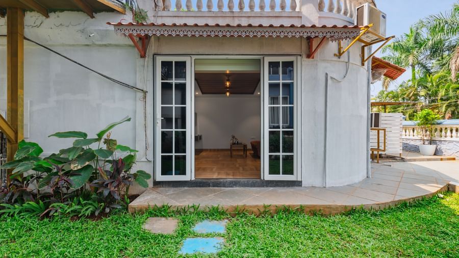Exterior view of a villa at Mayur Retreat with a private lawn, outdoor seating, and a staircase leading to the upper balcony.