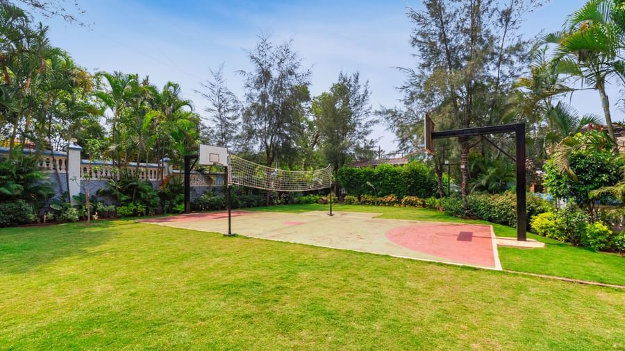 Outdoor volleyball and basketball court surrounded by trees at Mayur Retreat.