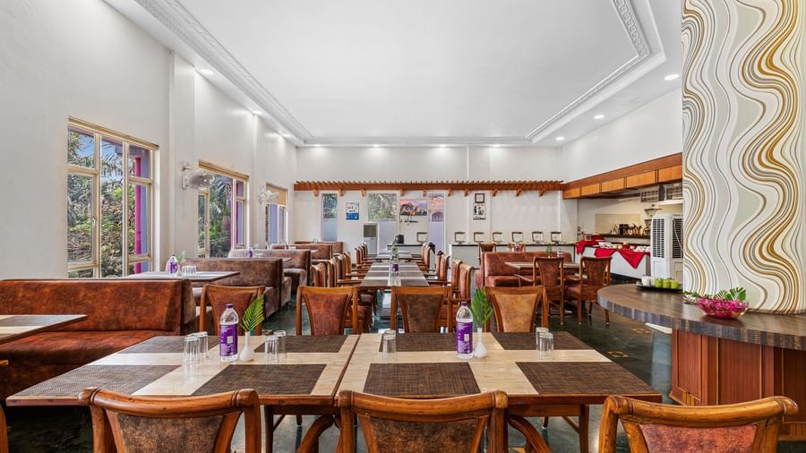 Indoor dining area with wooden furniture and colourful decor, part of The Darbar Restaurant at Mayur Retreat.