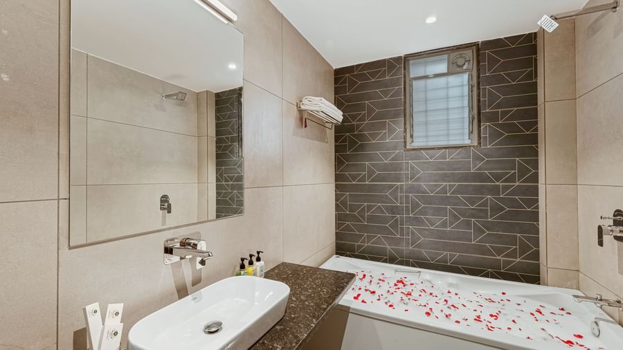 Modern bathroom at Mayur Retreat featuring a floral-decorated bathtub, sleek tiles, and a spacious layout.