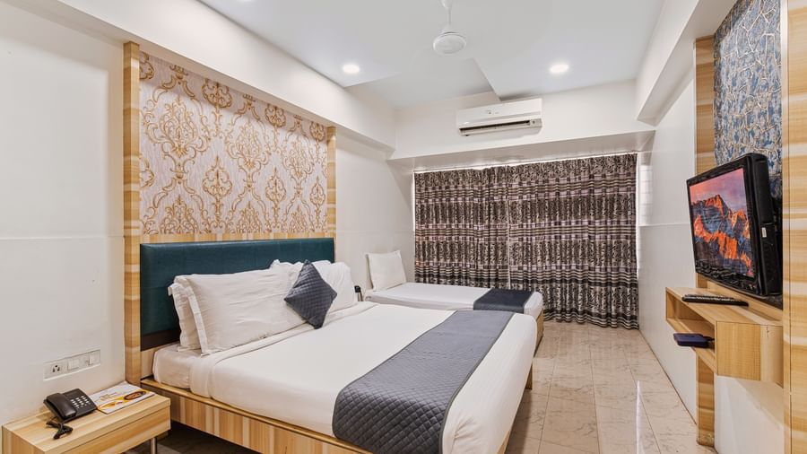 Modern hotel room with a king size bed and a singe bed at Mayur Retreat, contemporary lighting, and a flat-screen TV for a comfortable stay.