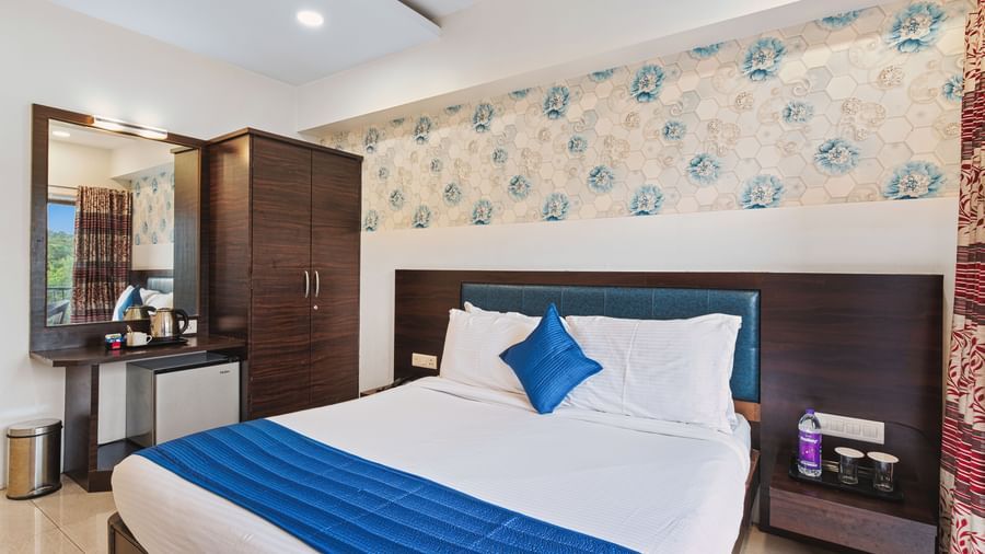 Contemporary bedroom at Mayur Retreat with blue-accented bed, floral wallpaper, and ambient lighting.