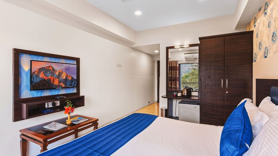 King size bed room at Mayur Retreat with a blue-accented bed, flat-screen TV, and wooden furniture.