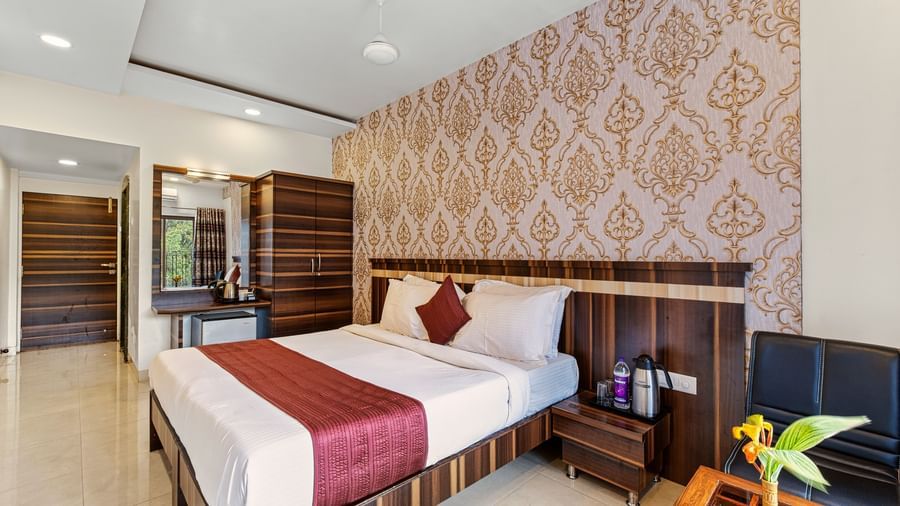 Comfortable bedroom at Mayur Retreat with two single beds, patterned wallpaper, and warm lighting.