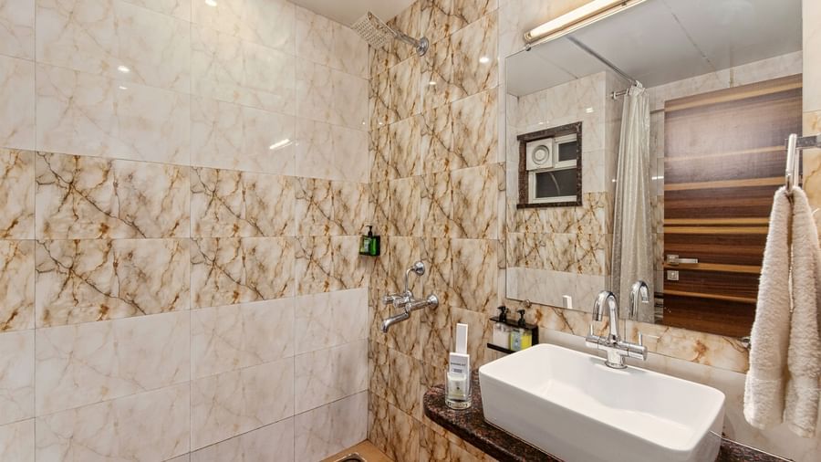 Luxurious bathroom with polished marble walls, a spacious vanity, and high-end fittings at Mayur Retreat.