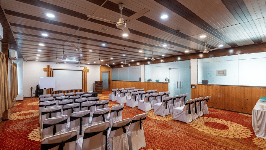 Spacious banquet hall at DLS Hotels On The Ganges with chairs aligned neatly and a white screen.