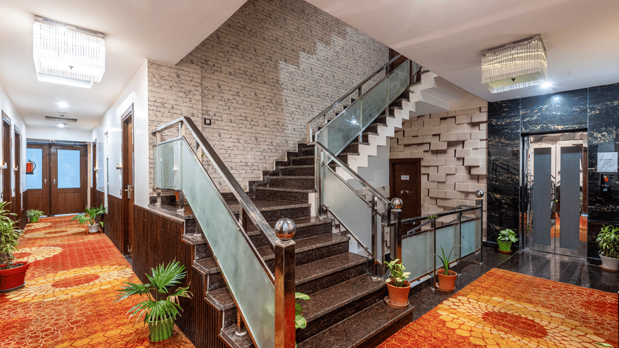 Corridor at DLS Hotels On The Ganges with stairs, potted plant and orange decorative carpet.