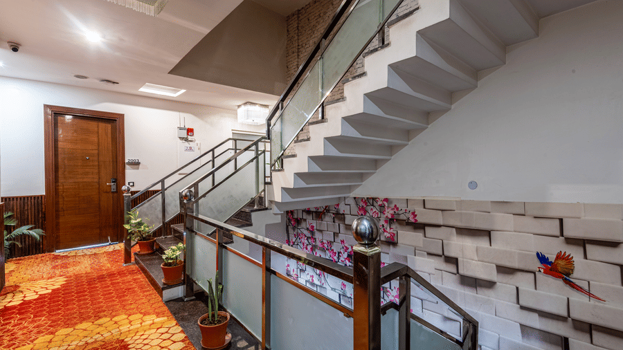 Stairs at DLS Hotels On The Ganges with orange decorative carpet and wooden doors.
