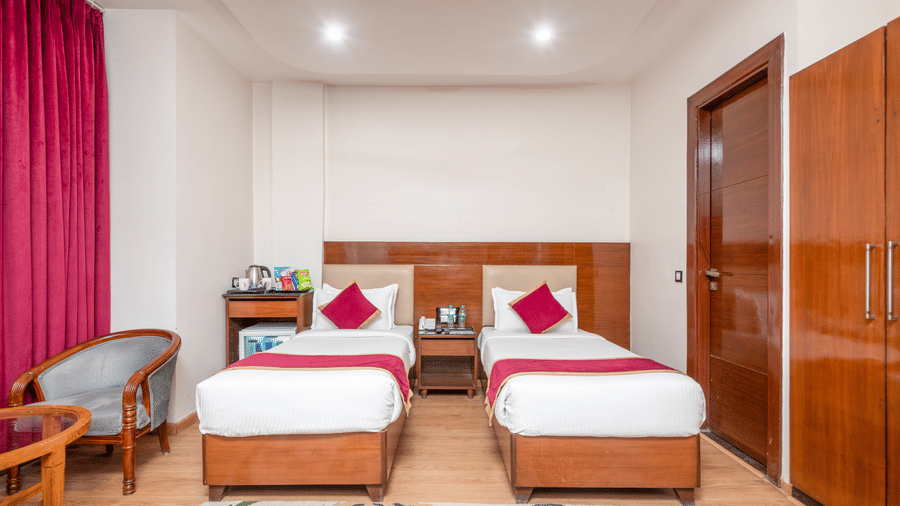 Twin bed room with pink curtains at DLS Hotels On The Ganges.
