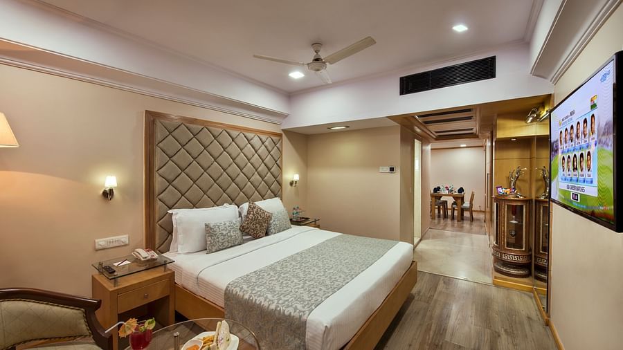 Hotel room with a bed, a TV, a lamp, and a small table with a snack tray - Lords Inn Vadodara