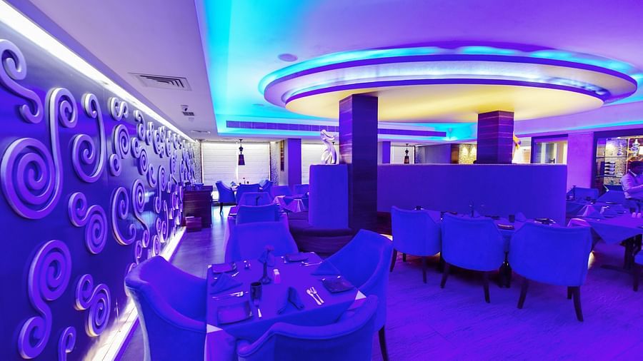 Aqua Restaurant with seating area and dim lighting at Swosti Grand, Bhubaneswar