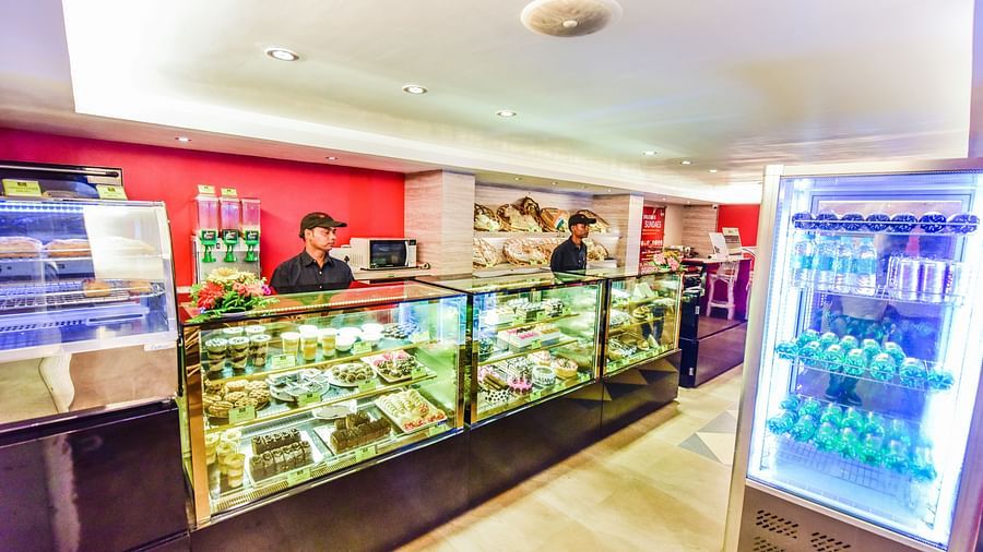Image of Brown N Cream shop with pastries and two men waiting the shop at Swosti Grand, Bhubaneswar
