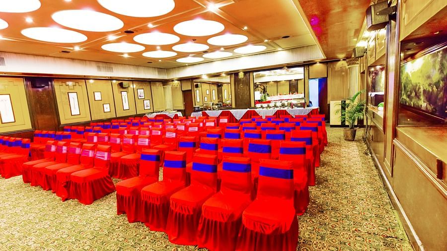 Side view of a banquet hall with chairs arranged and a fancy lighting on the ceiling at Swosti Grand, Bhubaneswar