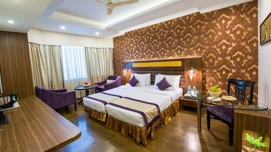 Side veiw of Grand Room witn bed and seating area and large windows on the side at Swosti Grand, Bhubaneswar