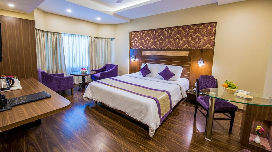Grand Room witn bed and seating area and large windows on the side at Swosti Grand, Bhubaneswar
