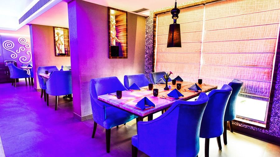 Oceana dining space with chairs arranged around the table and light hanging from the ceiling at Swosti Grand, Bhubaneswar
