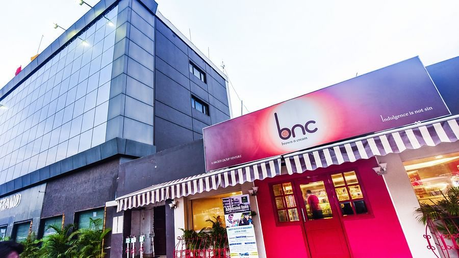 Facade of Brown N Cream with a tall building besides it at Swosti Grand, Bhubaneswar