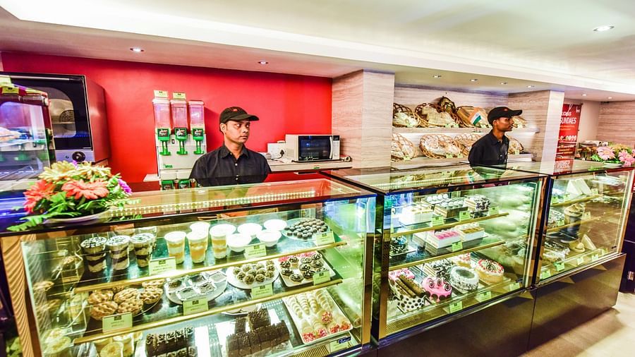 Image of Brown N Cream shop with pastries and two men waiting the shop at Swosti Grand, Bhubaneswar