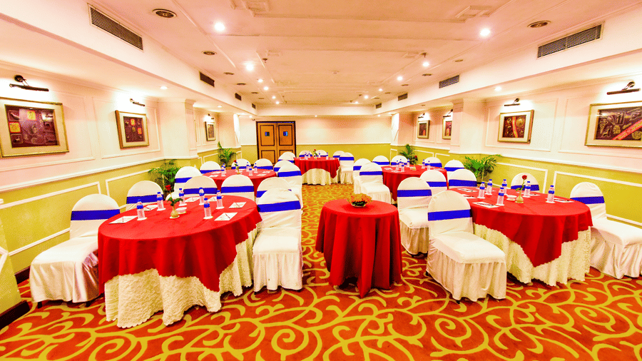 The banquet hall, brightly illuminated and beautifully decorated, is prepared for a memorable celebration.