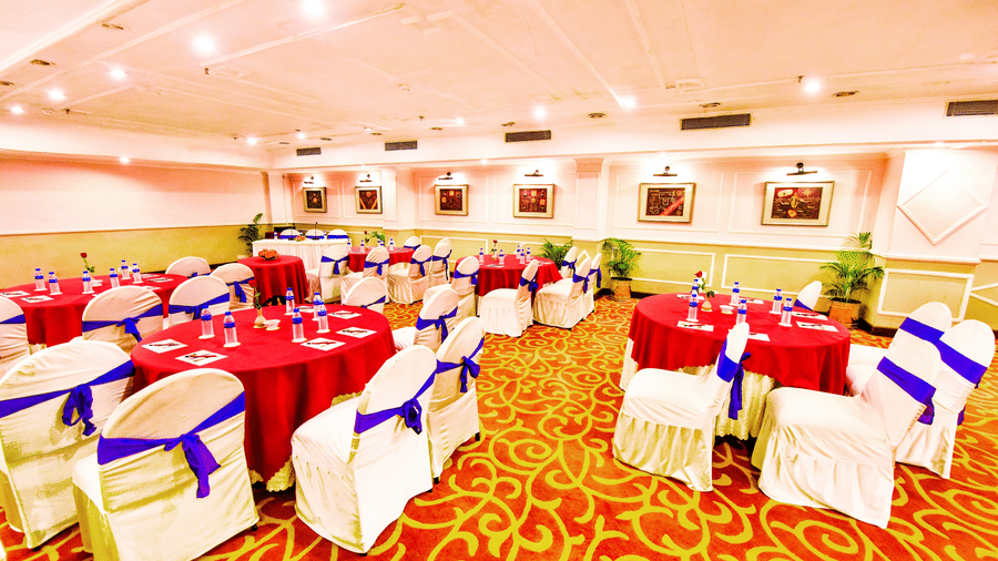 The banquet hall, brightly illuminated and beautifully decorated, is prepared for a memorable celebration.