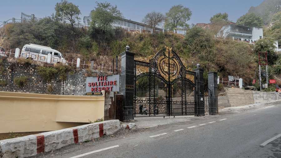 The main gated entrance with golden design and surrounding greenery providing secure access at The Solitaire Resort.