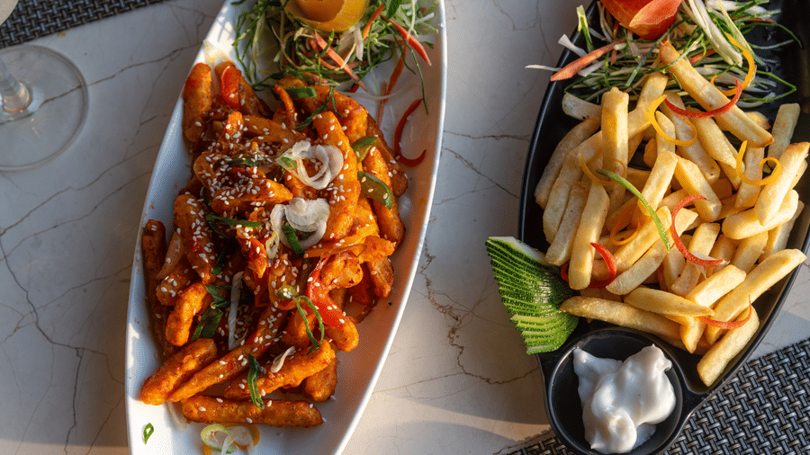 A delicious serving of fries and spicy pasta garnished with vegetables neatly plated for guests at The Solitaire Resort.