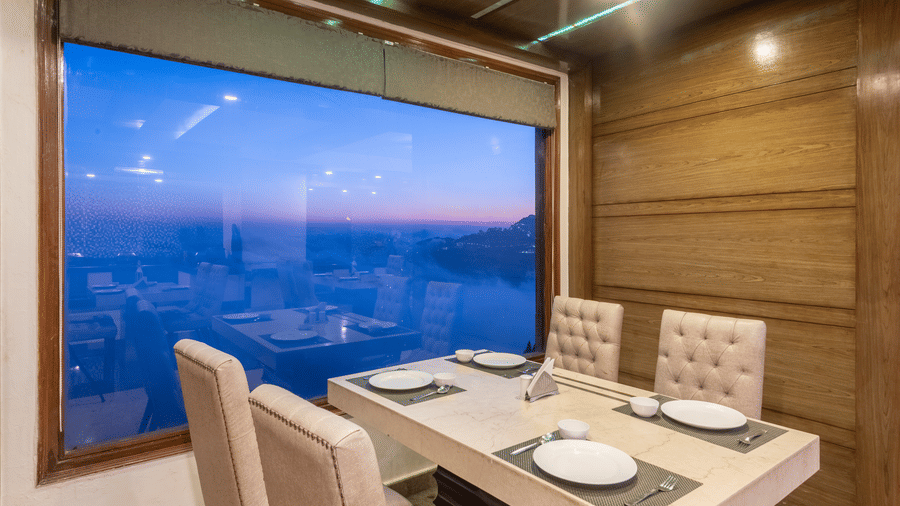 A dining table set beside a wide window offering panoramic views of the mountains, and valleys for guests at The Solitaire Resort.