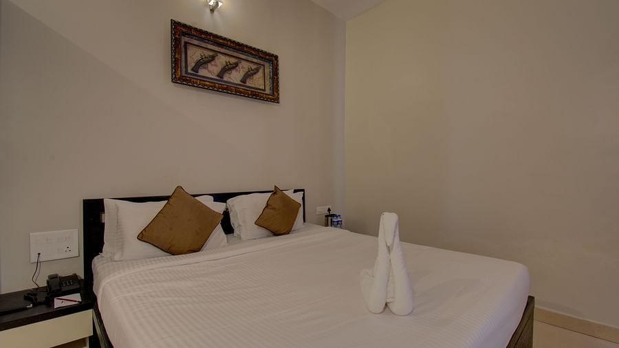 A bedroom with a bed, a side table and a wall art | Superior Room | Woodstock Resorts, Coorg