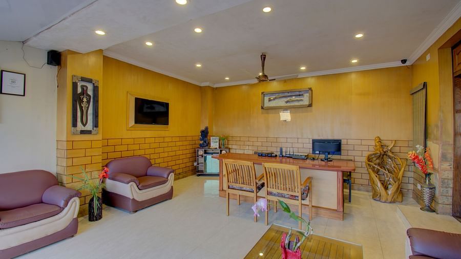 A reception area showcasing a television and additional seating near the reception desk | Woodstock Resorts, Coorg