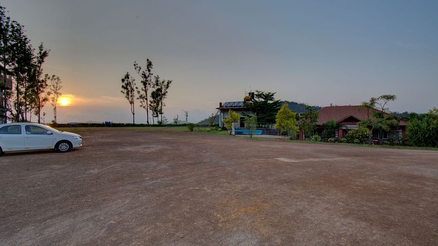 A car parked  on a tiled floor with a sunset view and greenery | Woodstock Resorts, Coorg