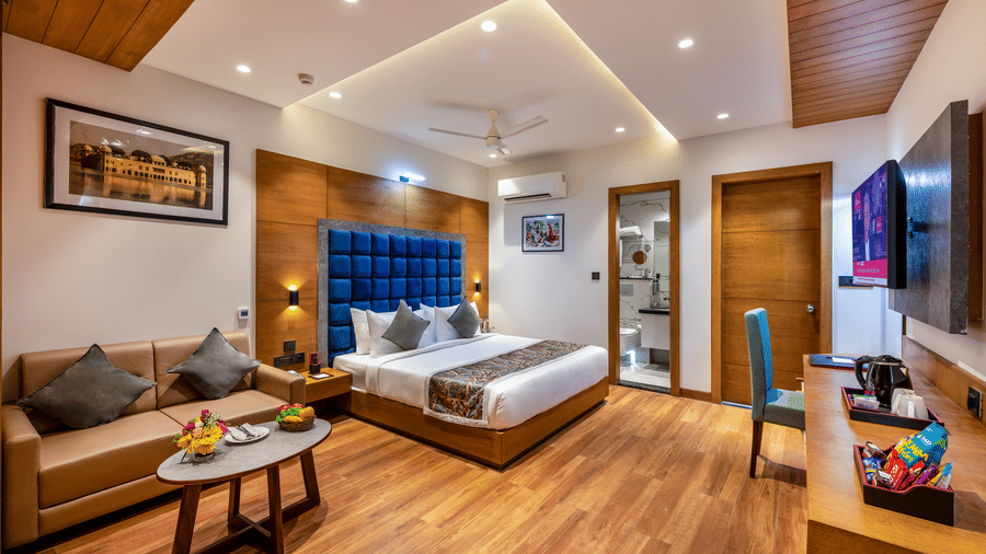 Lords hotel  Exhecutive room with bed, sofa seating area, wood flooring, and wall-mounted TV.