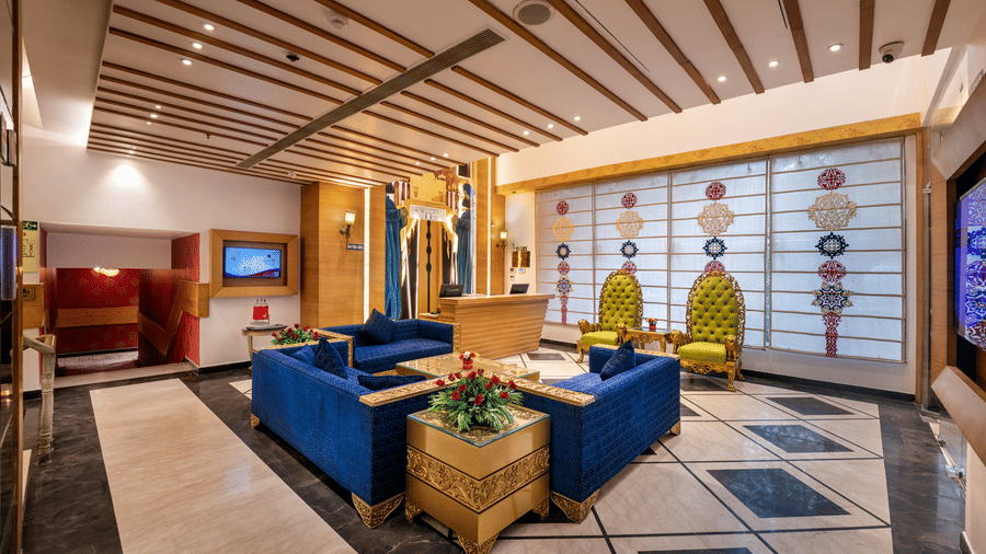View of the lobby lounge at Lords Inn Amritsar with blue sofas, decorative panels, indoor plants, and warm ambient lighting.