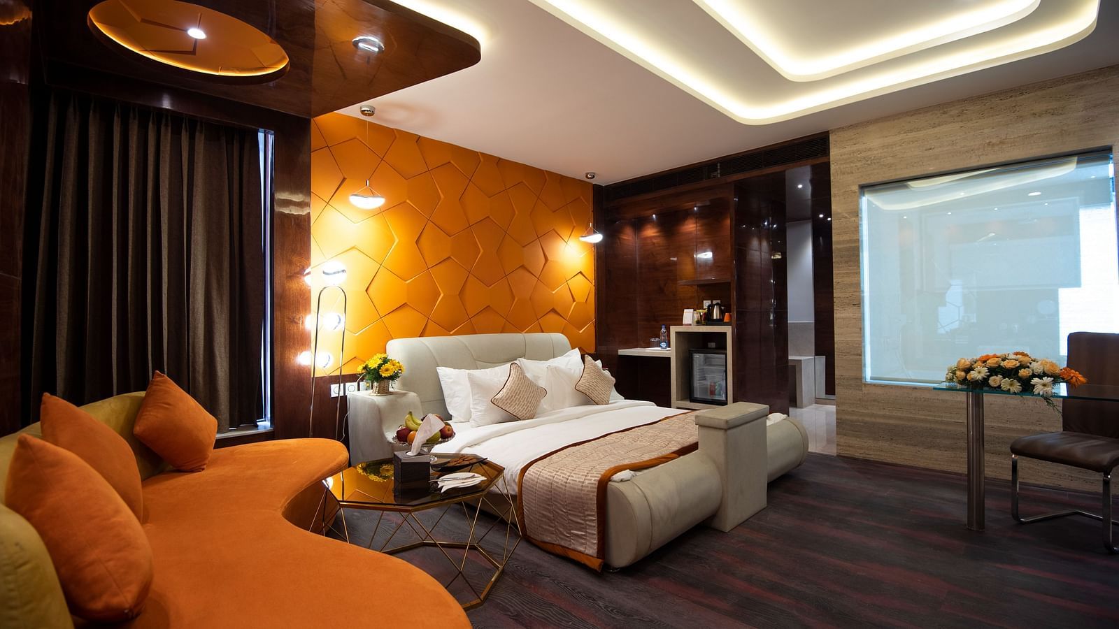 Junior Suite decked with a comfy bed and orange sofa at Hotel Park Elanza, Coimbatore