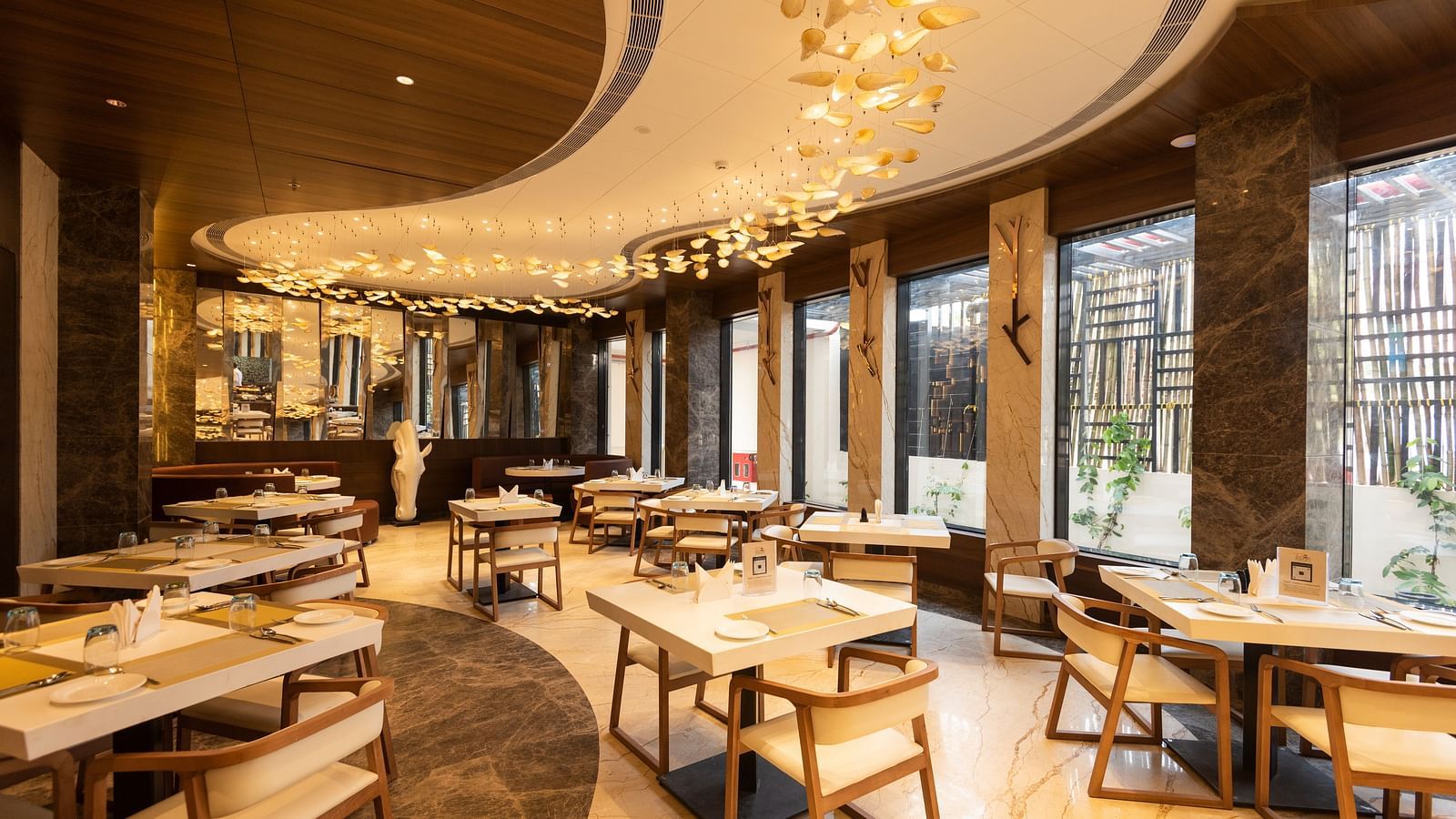 a warmly-lit interior of Tempt Asian Restaurant decked with elegant seating arrangements at Hotel Park Elanza, Coimbatore
