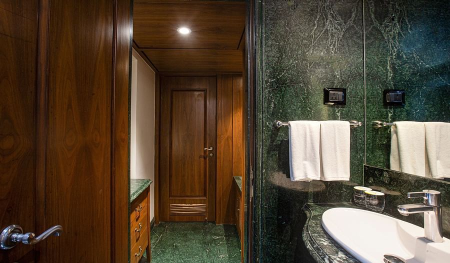 A Rajasthani-themed bathroom illuminated by dim lights, featuring elegant marble furnishings and traditional design elements.