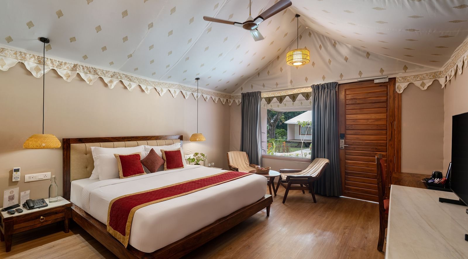 corner view image of the luxury tent villa featuring a comfortable king size bed and a huge window in the room at aranya vilas