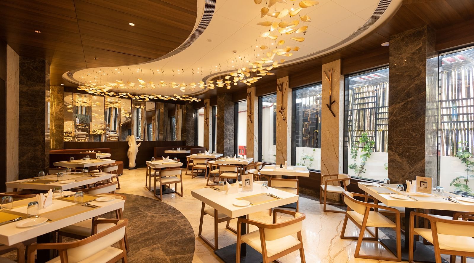 a warmly-lit interior of Tempt Asian Restaurant decked with elegant seating arrangements at Hotel Park Elanza, Coimbatore
