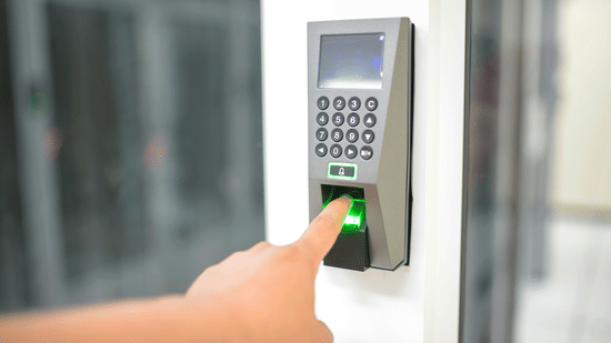A person using a biometric fingerprint scanner on a door access panel.
