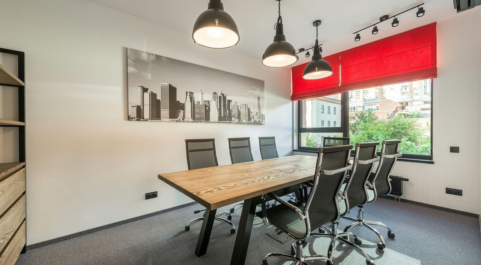 An image of a board room with chair and a table with three lights hanging from the ceiling