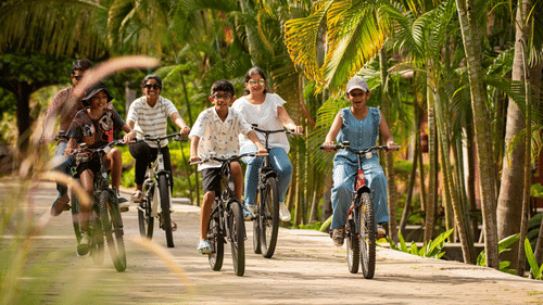 kids Cycling on a pathway next to coconut trees  - Ibex River Resort, Pollachi