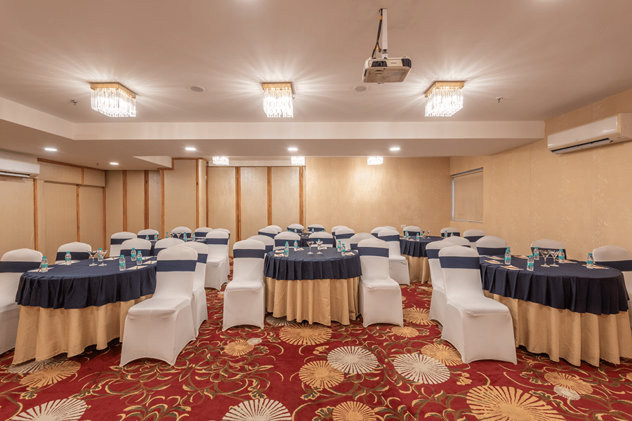 Conference room set up with rows of covered chairs and tables for a seminar or meeting at Mango Grove Hotel.